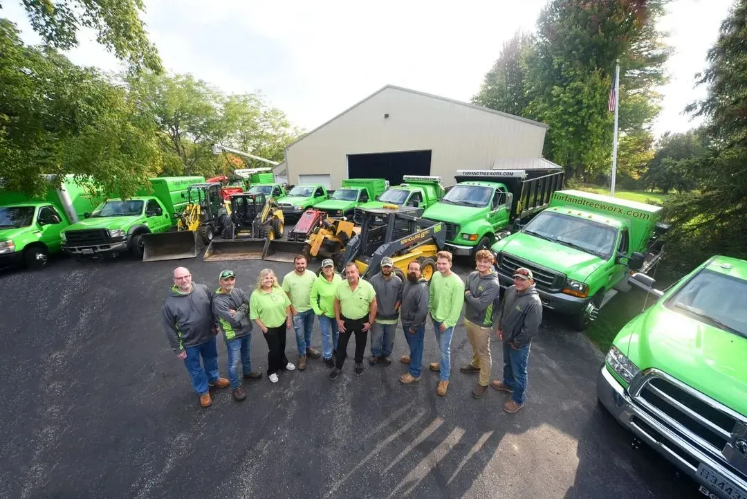 The Turf & Tree Worx team in front of their green trucks